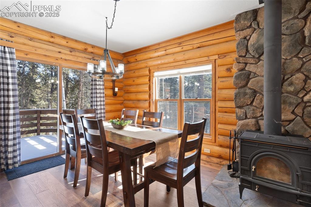 Image 14 of 50: Dining area featuring a wood stove, Rear slider to bach deck