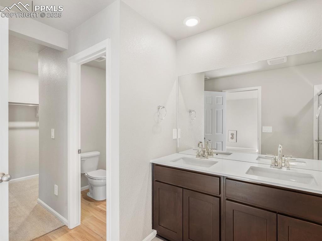 Image 20 of 27: Bathroom with double vanity, a spacious closet, and light wood finished flo