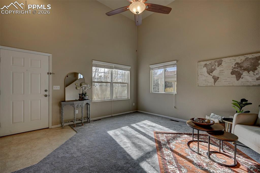 Image 6 of 44: Beautiful entryway into the living room with new carpet, high ceilings, and