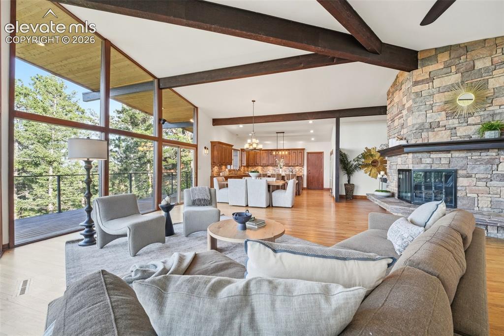Image 10 of 48: Open-concept living space featuring a stone fireplace, wood-finish flooring