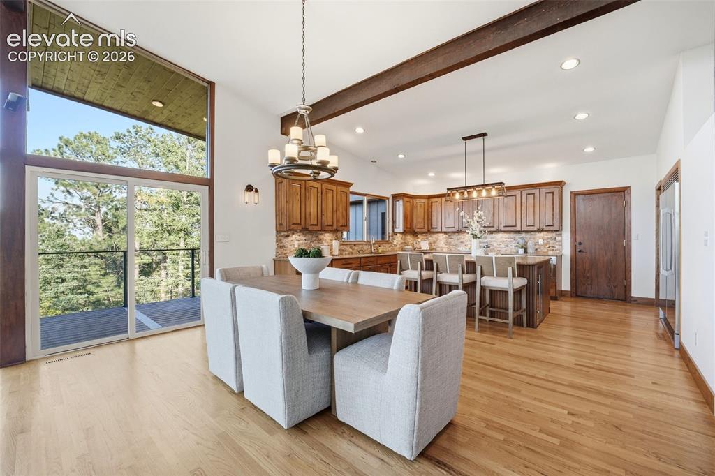 Image 11 of 48: Open-concept dining and kitchen area featuring wood-finish flooring, a vaul