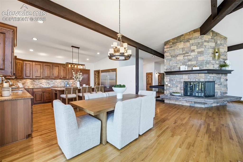 Image 12 of 48: Open-concept living area featuring a stone-clad fireplace, wood-finish floo
