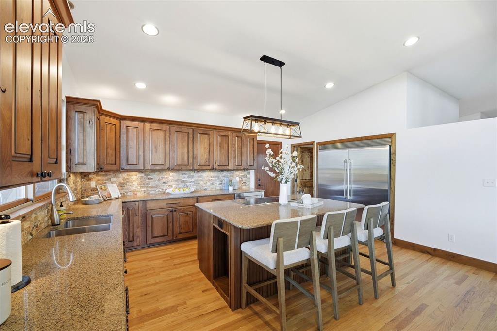 Image 15 of 48: Kitchen featuring wood cabinetry, stone countertops, a tiled backsplash, wo