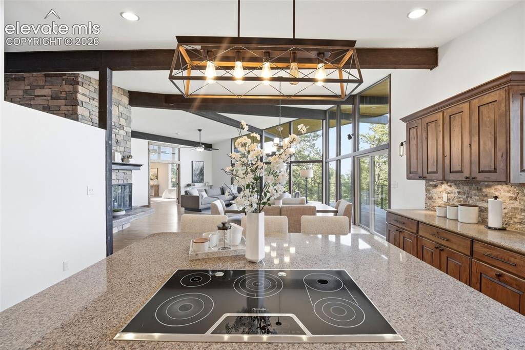 Image 18 of 48: Kitchen island with an integrated cooktop, stone-finish countertop, and dec