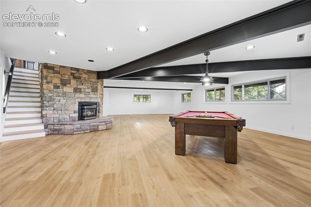 Image 33 of 48: Spacious room featuring light wood-finish flooring, a stacked stone firepla