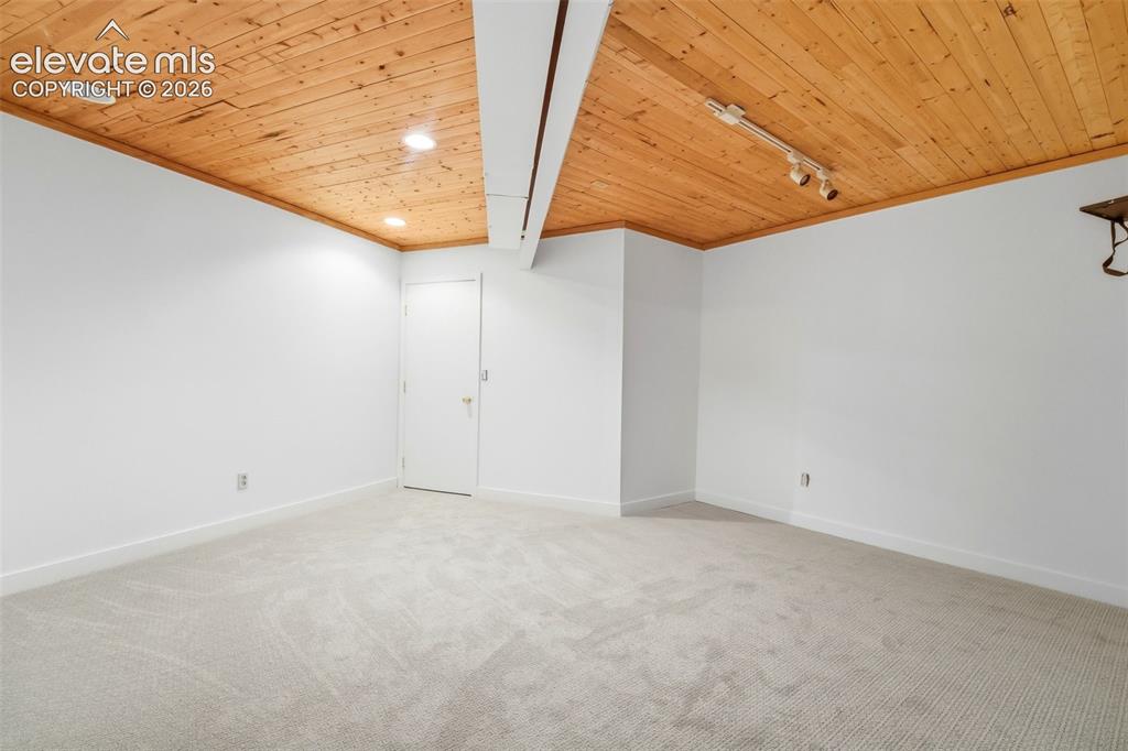 Image 38 of 48: Spacious room featuring a wood-panel ceiling, recessed lighting, and track 