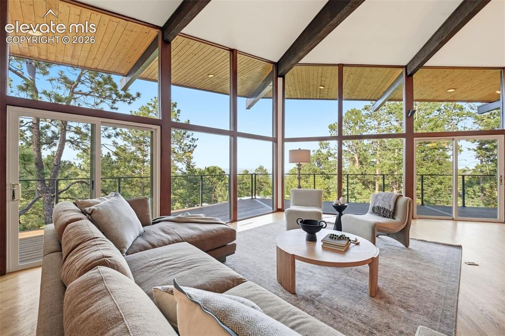 Image 4 of 48: Living area featuring expansive floor-to-ceiling windows, wood-finish floor