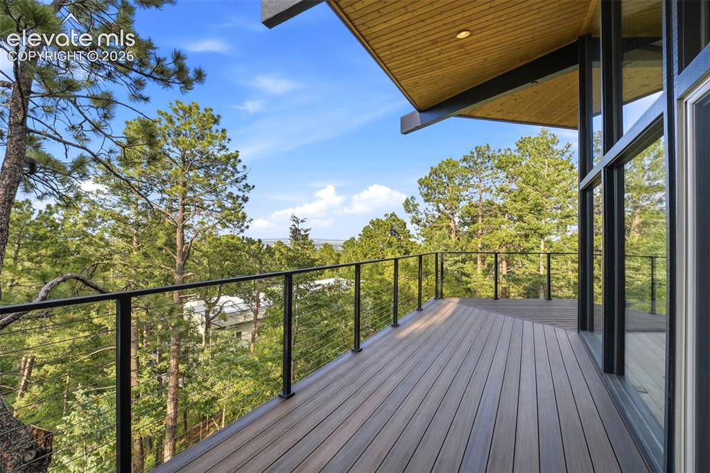 Image 42 of 48: Expansive outdoor deck featuring wood-finish flooring, black metal cable ra
