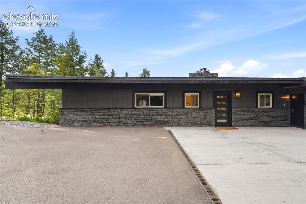 Image 44 of 48: Modern exterior featuring dark horizontal siding and a stacked stone facade