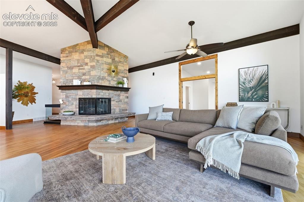 Image 9 of 48: Living area featuring a floor-to-ceiling stone fireplace, exposed ceiling b