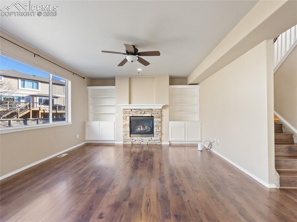Image 10 of 46: Unfurnished living room with dark wood-style floors, a ceiling fan, and a f