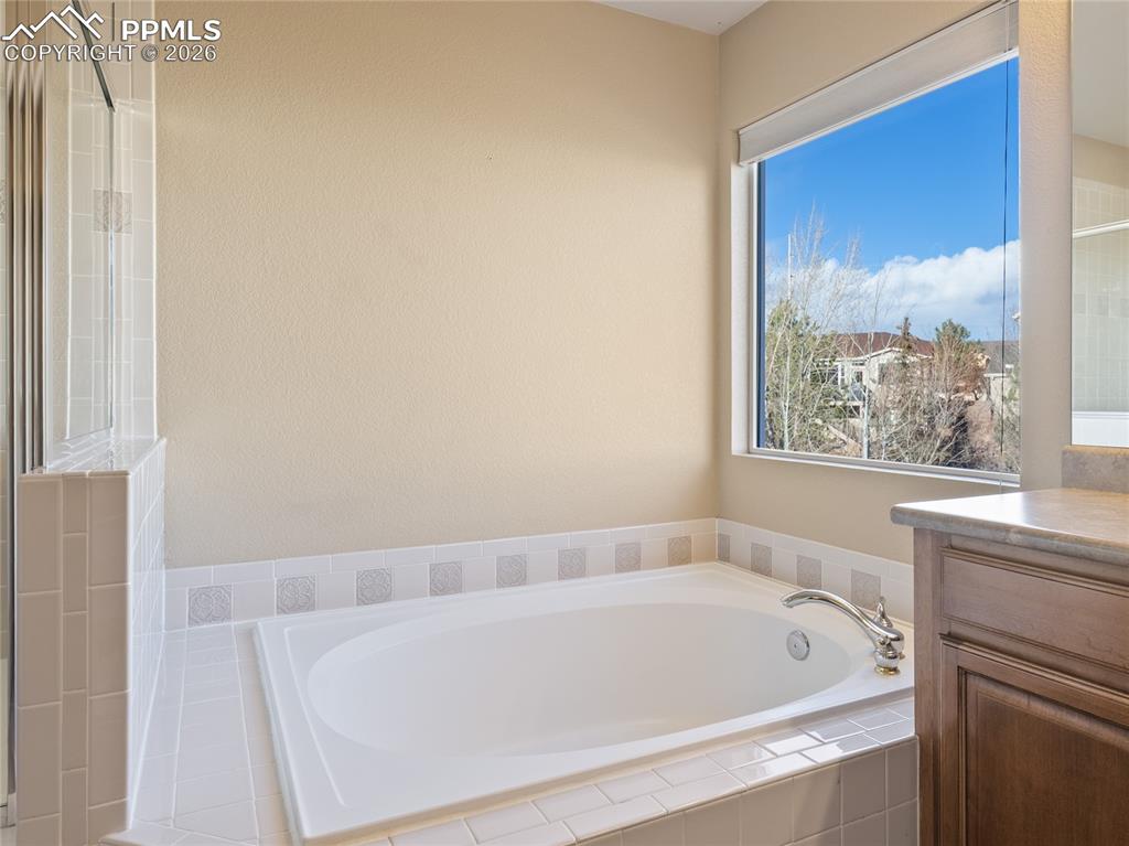 Image 24 of 46: Full bath with a garden tub, vanity, and a shower with shower door