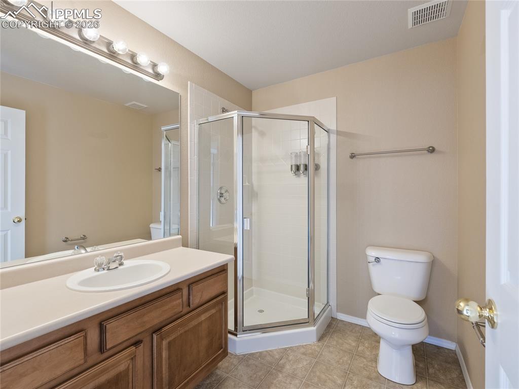 Image 29 of 46: Bathroom with a stall shower, vanity, and light tile patterned floors