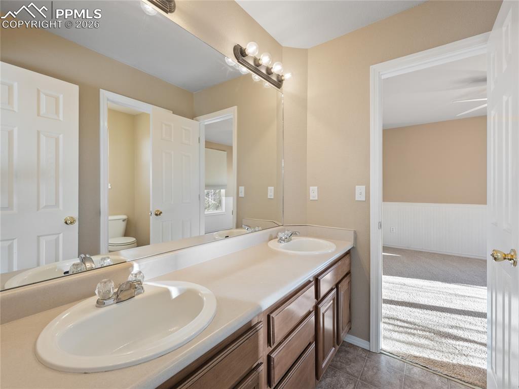 Image 32 of 46: Jack and Jill bathroom with double vanity, light colored carpet, and wainsc