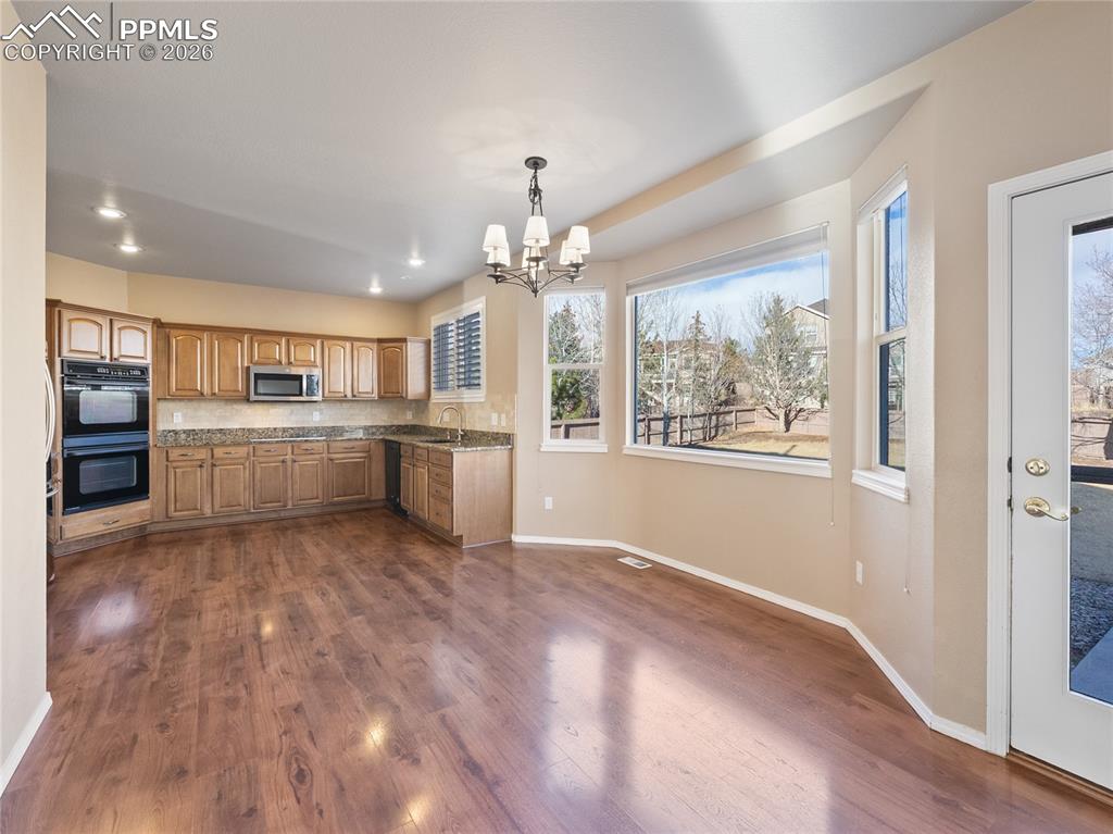 Image 4 of 46: Kitchen featuring a chandelier, black appliances, dark wood-style floors, l