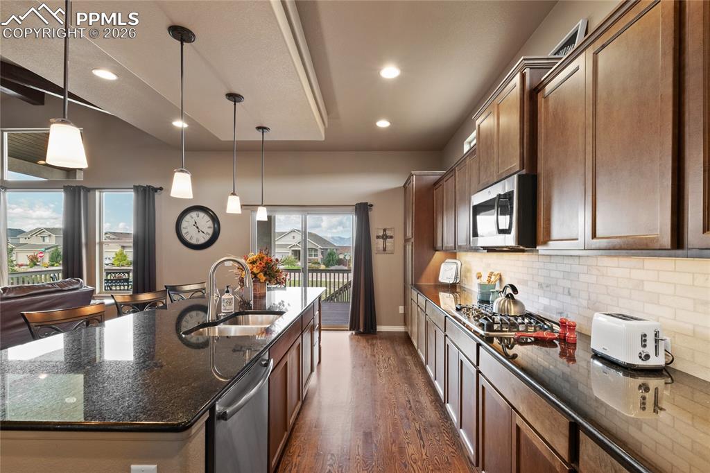 Image 19 of 49: Granite countertops, gas cooktop and all stainless steel appliances. Hardwo