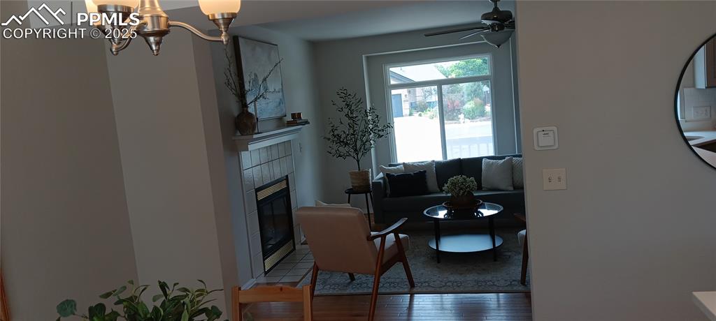Image 15 of 45: Living room featuring a tiled fireplace, ceiling fan, and oak floors