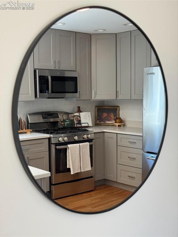 Image 35 of 45: Kitchen featuring gray cabinetry, stainless steel appliances, decorative ba