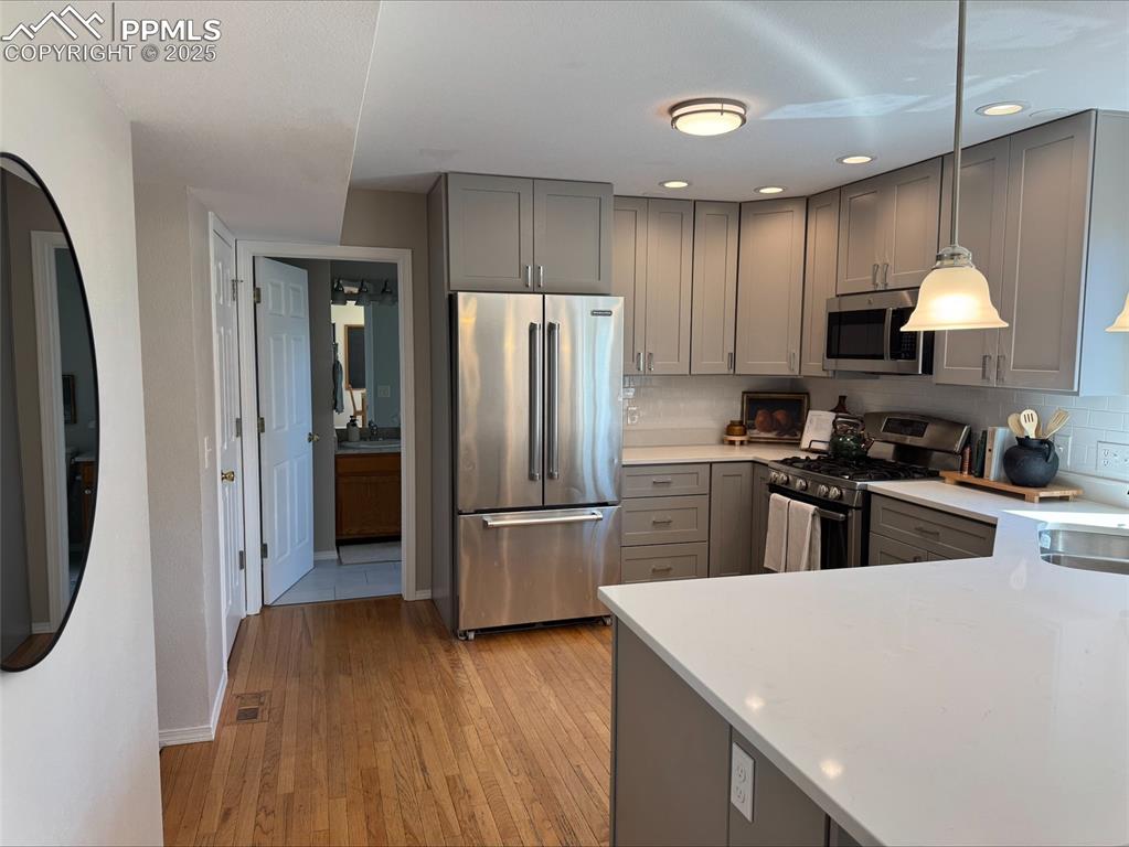 Image 4 of 45: Kitchen featuring gray cabinets, stainless steel appliances, light countert