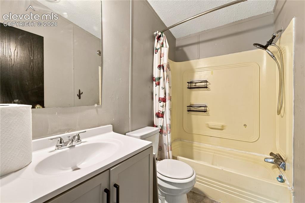 Image 15 of 19: Bathroom featuring a built-in tub with an integrated shower, a vanity with