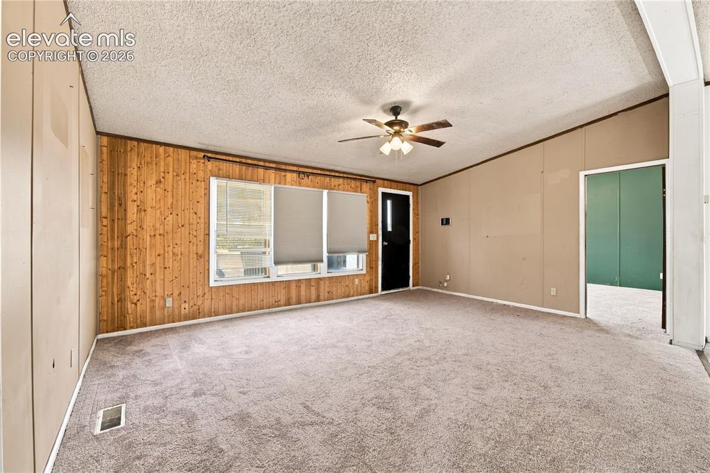 Image 4 of 19: Carpeted flooring, wood paneling, ceiling fan, natural light, and a dark-pa