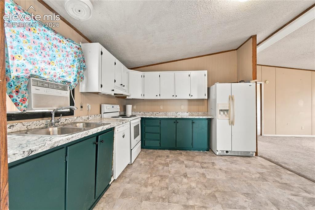 Image 6 of 19: Kitchen featuring white upper cabinetry, teal lower cabinetry, white applia