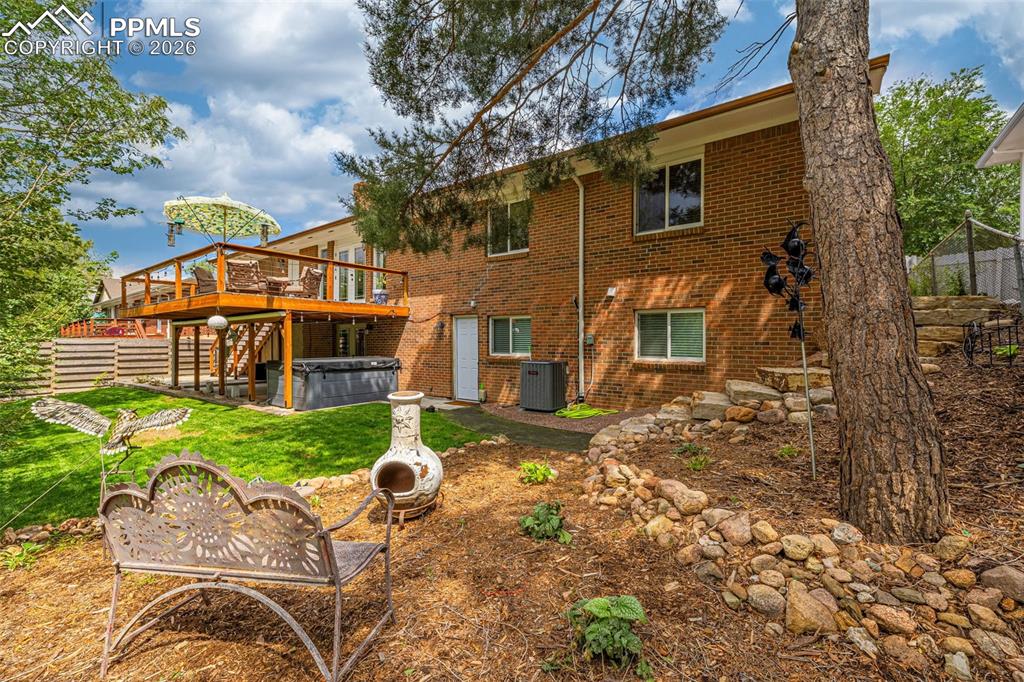 Image 42 of 44: Rear view of house featuring a hot tub, brick siding, a patio, and a wooden
