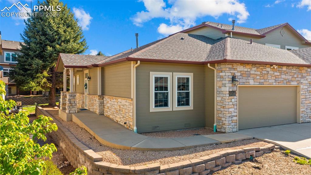 Image 1 of 31: Exterior featuring stone veneer accents, an attached two-car garage, covere