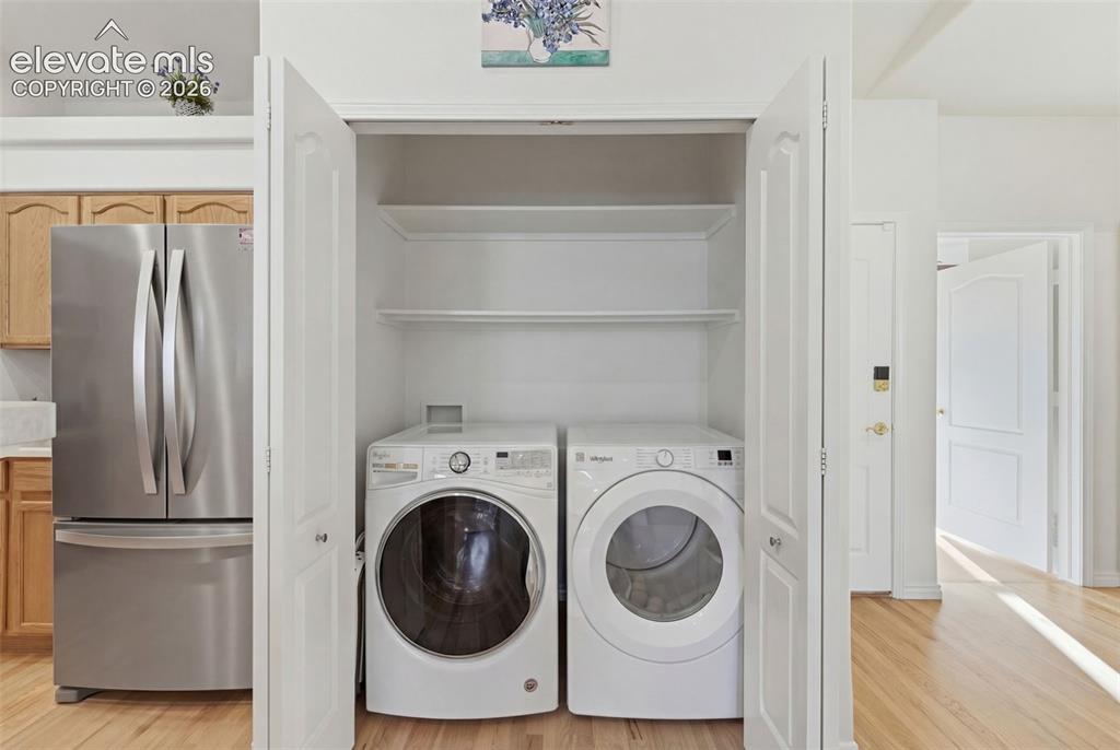Image 10 of 31: Dedicated laundry closet with stacked shelving, front-loading washer, and d