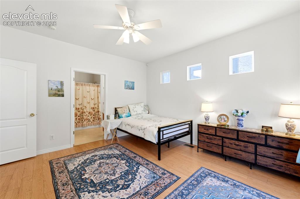 Image 12 of 31: Spacious room featuring wood-finish flooring, a ceiling fan, and multiple h