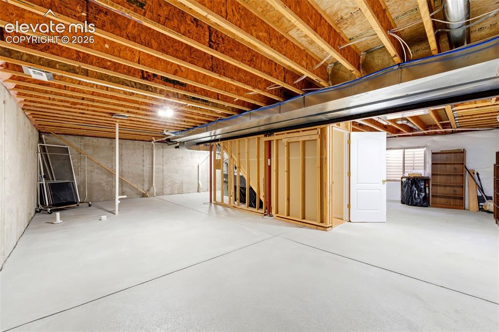 Image 20 of 31: Unfinished basement featuring exposed wood joists, concrete foundation wall
