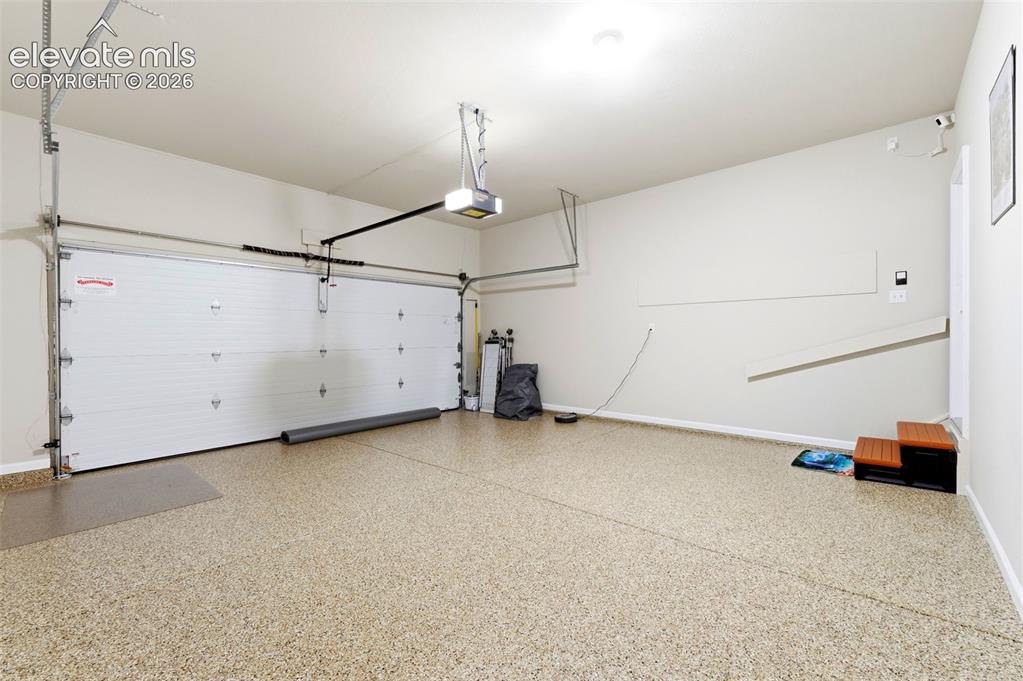 Image 22 of 31: Spacious garage featuring an epoxy-coated floor, automatic garage door open