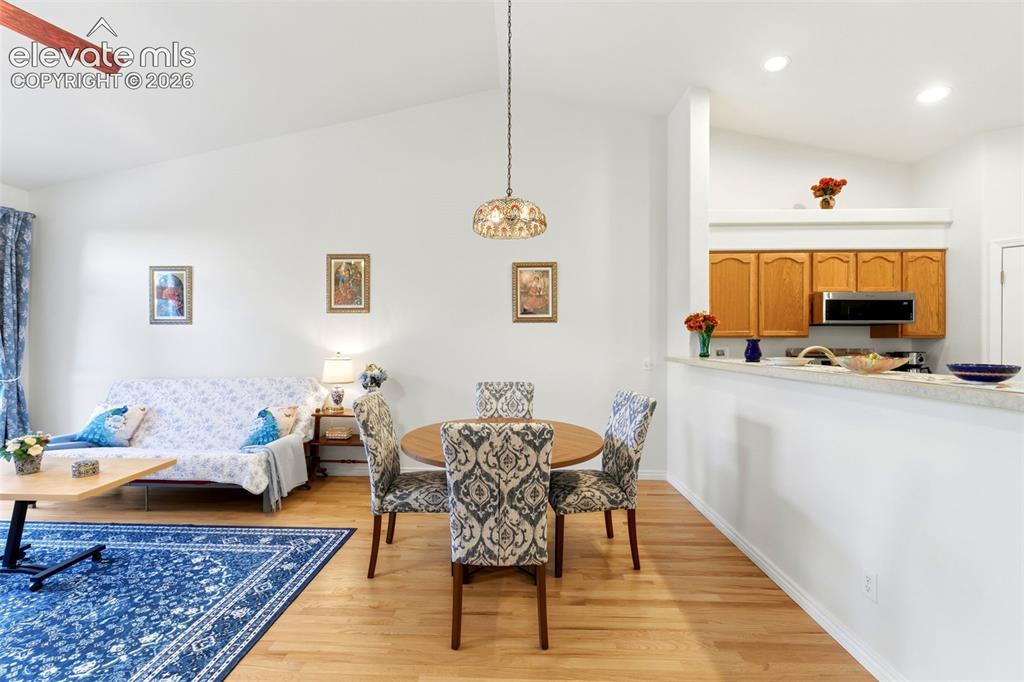Image 5 of 31: Open-concept living and dining area featuring wood-finish flooring, vaulted