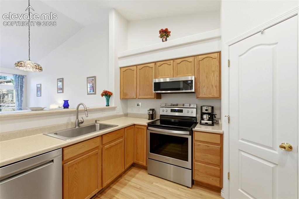 Image 7 of 31: Kitchen featuring wood-finish cabinetry, stainless steel appliances, and li