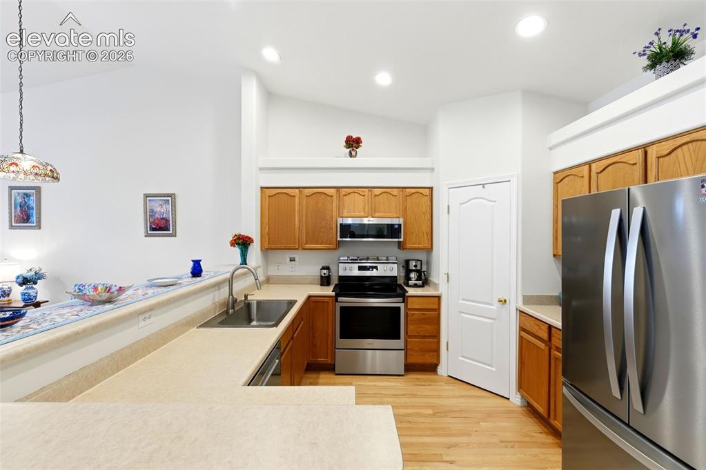 Image 9 of 31: Kitchen featuring vaulted ceilings with recessed lighting, light wood-finis