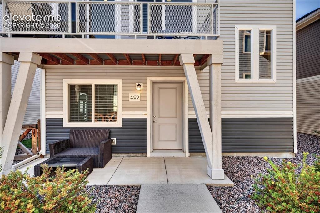 Image 32 of 48: Ground-level patio with concrete slab, exterior wall sconce, and two-tone h