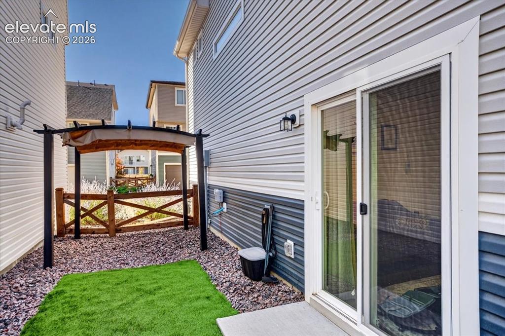 Image 4 of 48: A sliding glass door opens to the fenced yard with low-maintenance turf and