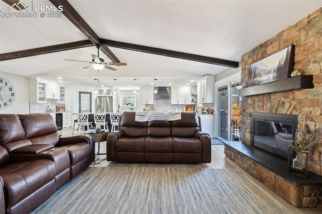 Image 10 of 49: Cozy open living room with a vaulted beam ceiling, stone wood-burning firep