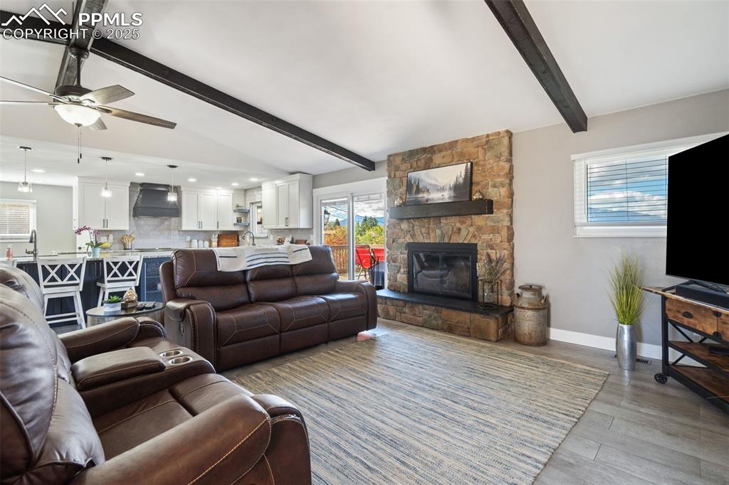 Image 9 of 49: Open concept floor plan with vaulted beamed ceilings, wood-burning stone fi