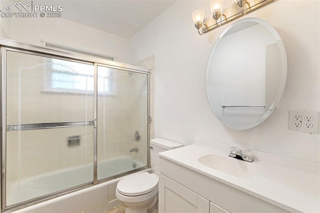 Image 10 of 17: Bathroom with shower / bath combination with glass door and vanity