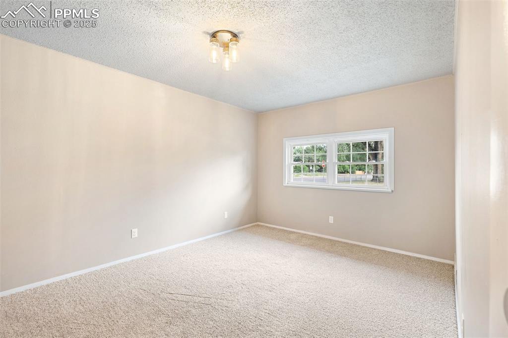Image 11 of 17: Carpeted empty room featuring a textured ceiling and baseboards