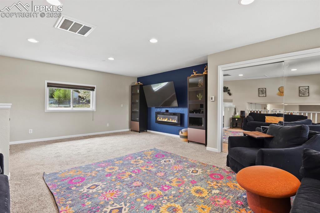 Image 17 of 38: This expansive living area features recessed lighting, a modern wall-mounte