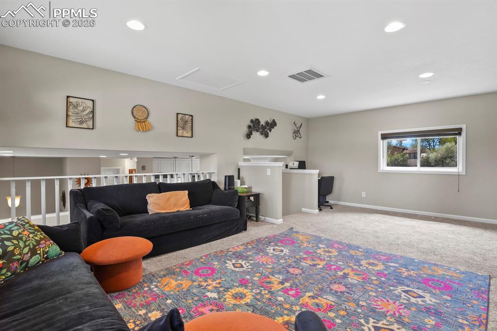 Image 18 of 38: Open concept living area with carpeting, recessed lighting and a window pro