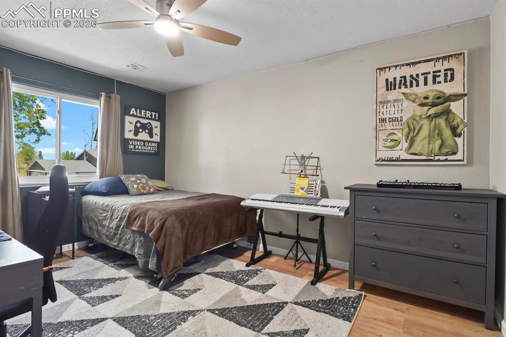 Image 19 of 38: This bedroom features a window providing natural light, hardwood flooring a
