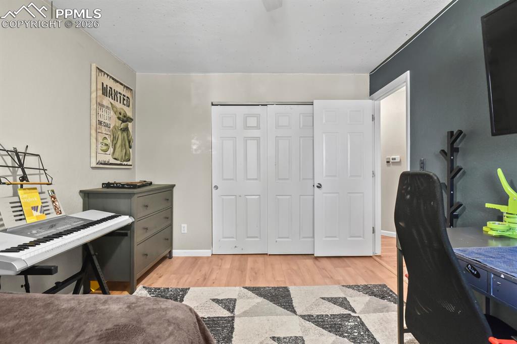 Image 20 of 38: This bedroom features hardwood flooring, a light gray painted wall and a co