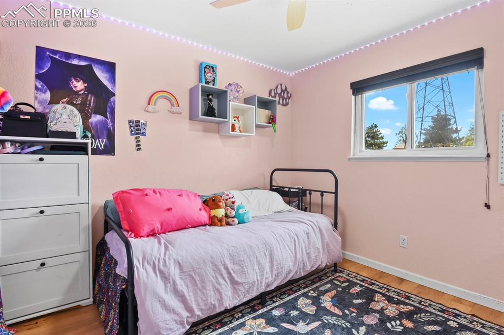 Image 22 of 38: This room features a window with a dark roller blind and hardwood flooring