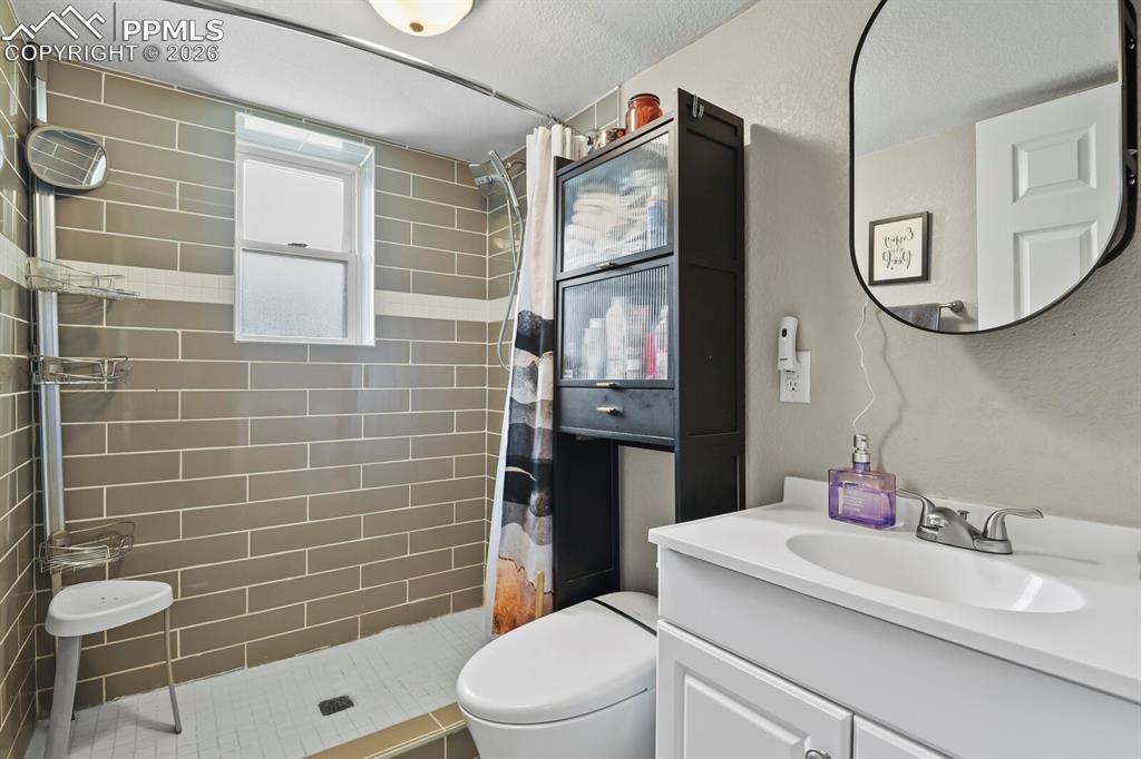 Image 28 of 38: Well-appointed bathroom featuring a white vanity, wall-mounted mirror and a