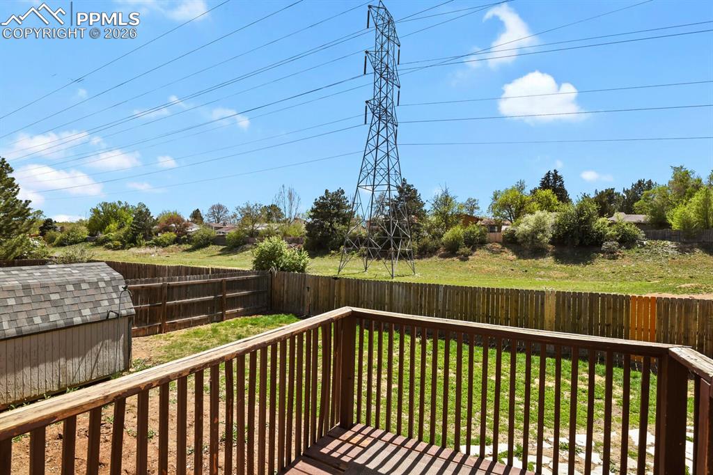 Image 33 of 38: The property features a wood deck overlooking a fenced yard with a shed, of