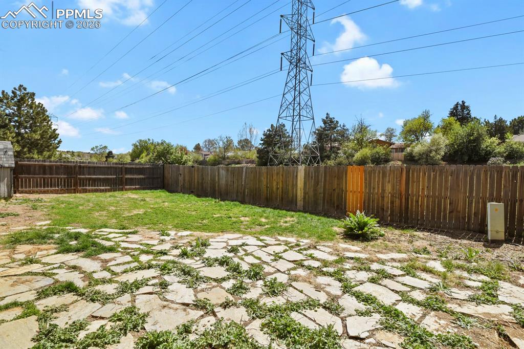 Image 34 of 38: The property features a fenced backyard with a lawn area and a stone patio
