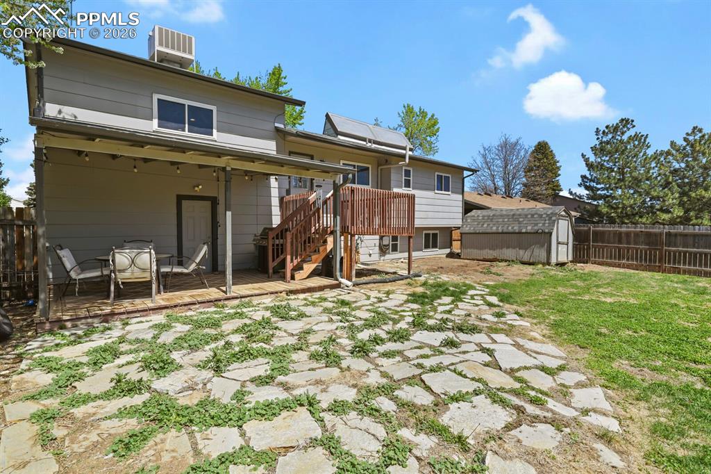 Image 35 of 38: The property features a spacious backyard with a stone patio, a wooden deck